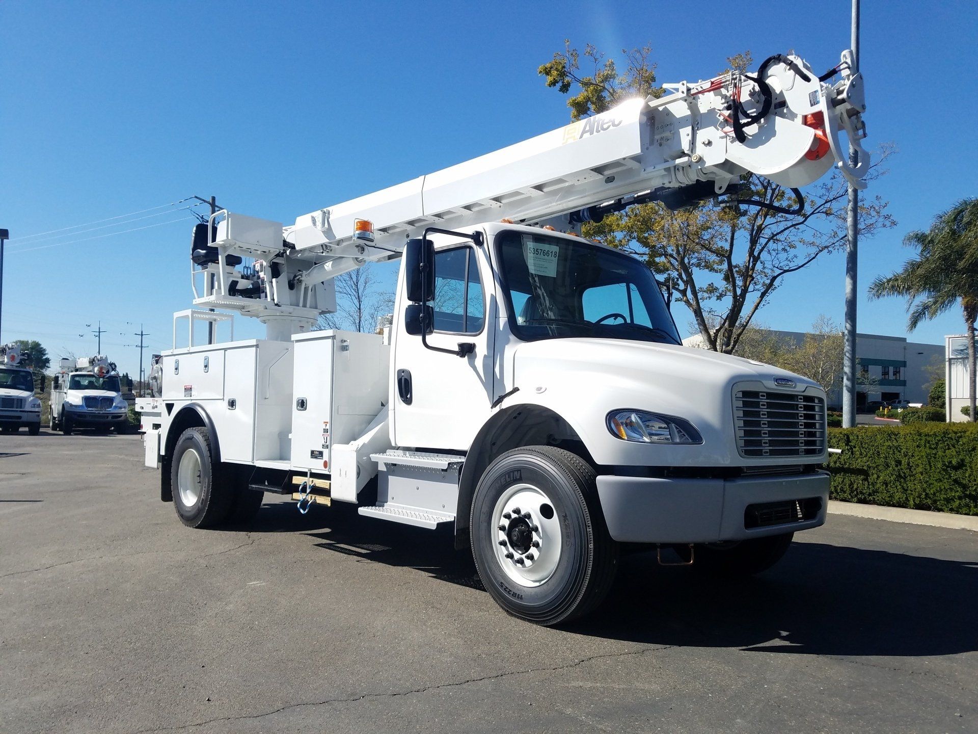 White utility bucket truck parked outdoors under a clear blue sky.