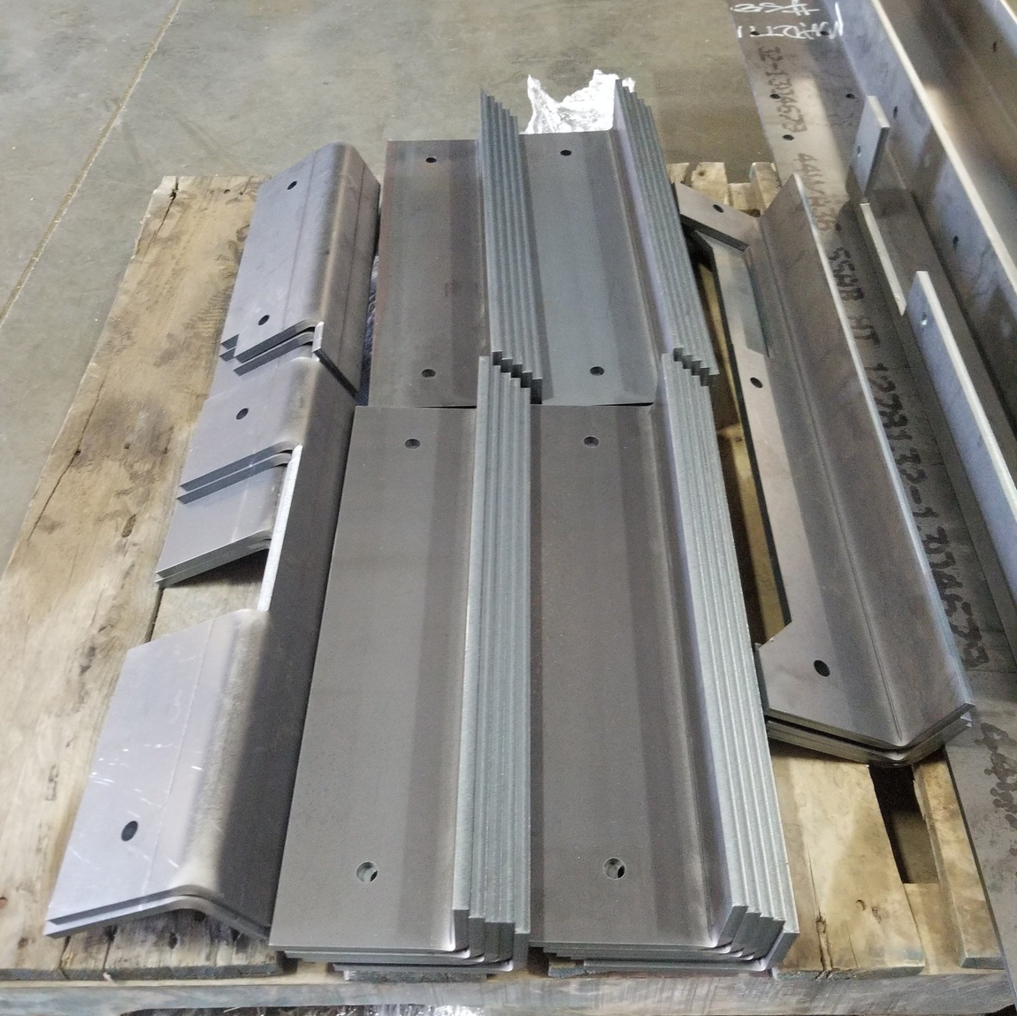Metal roof panels stacked on a wooden pallet in a warehouse or construction yard.