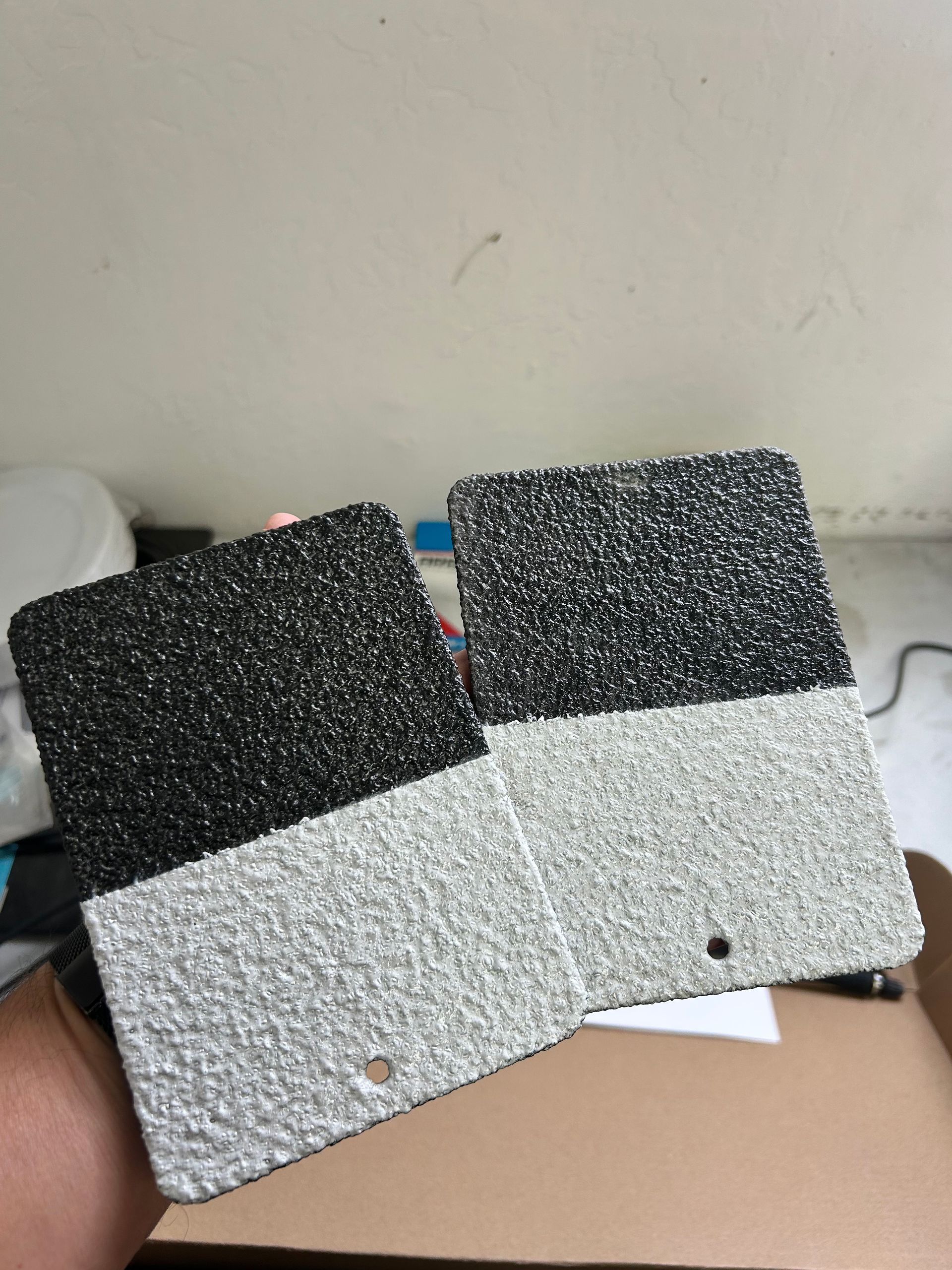 Two black-and-white textured fabric pieces held over a cardboard box