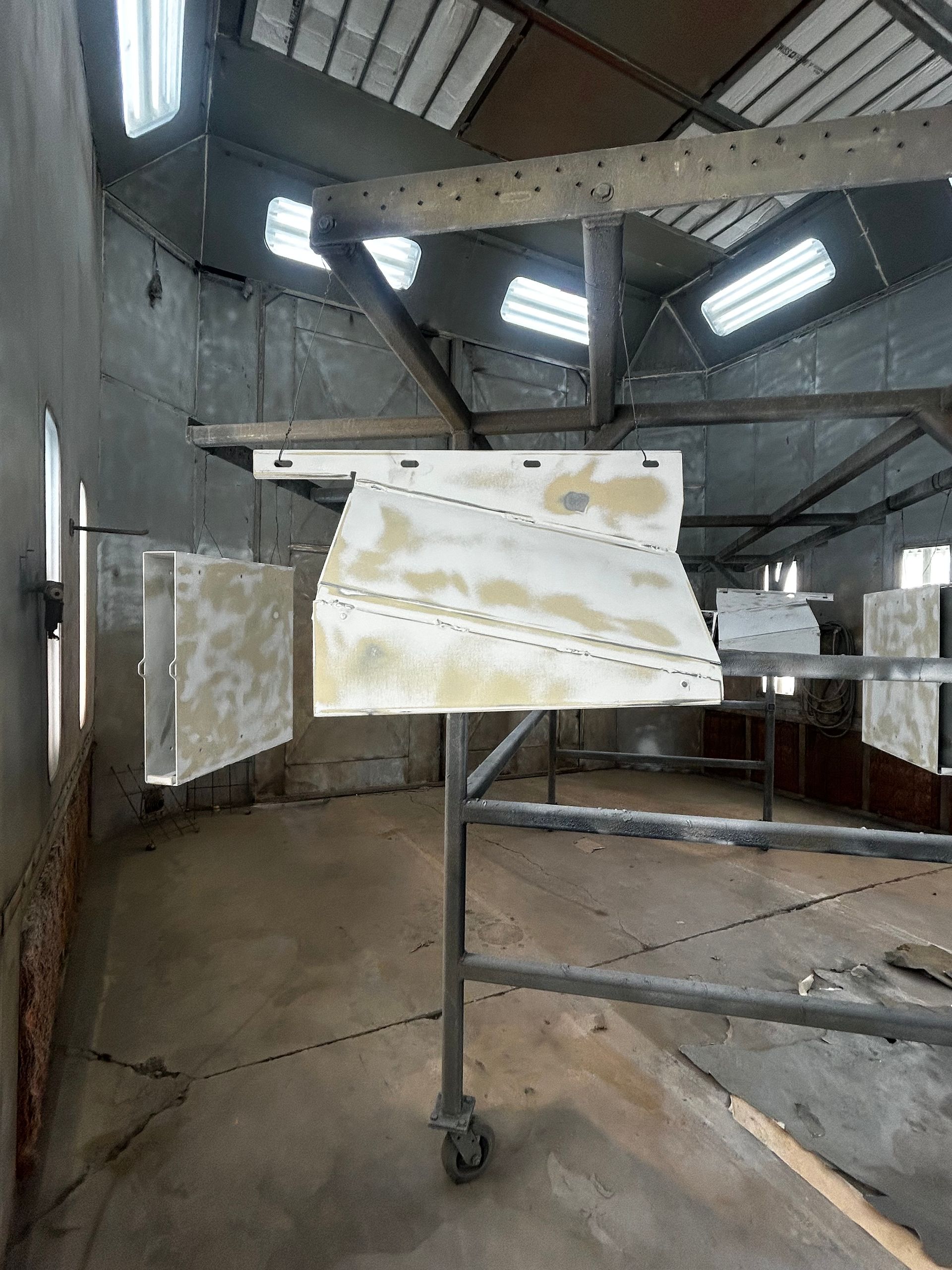 Damaged sign on a wheeled stand inside a concrete industrial room with skylights