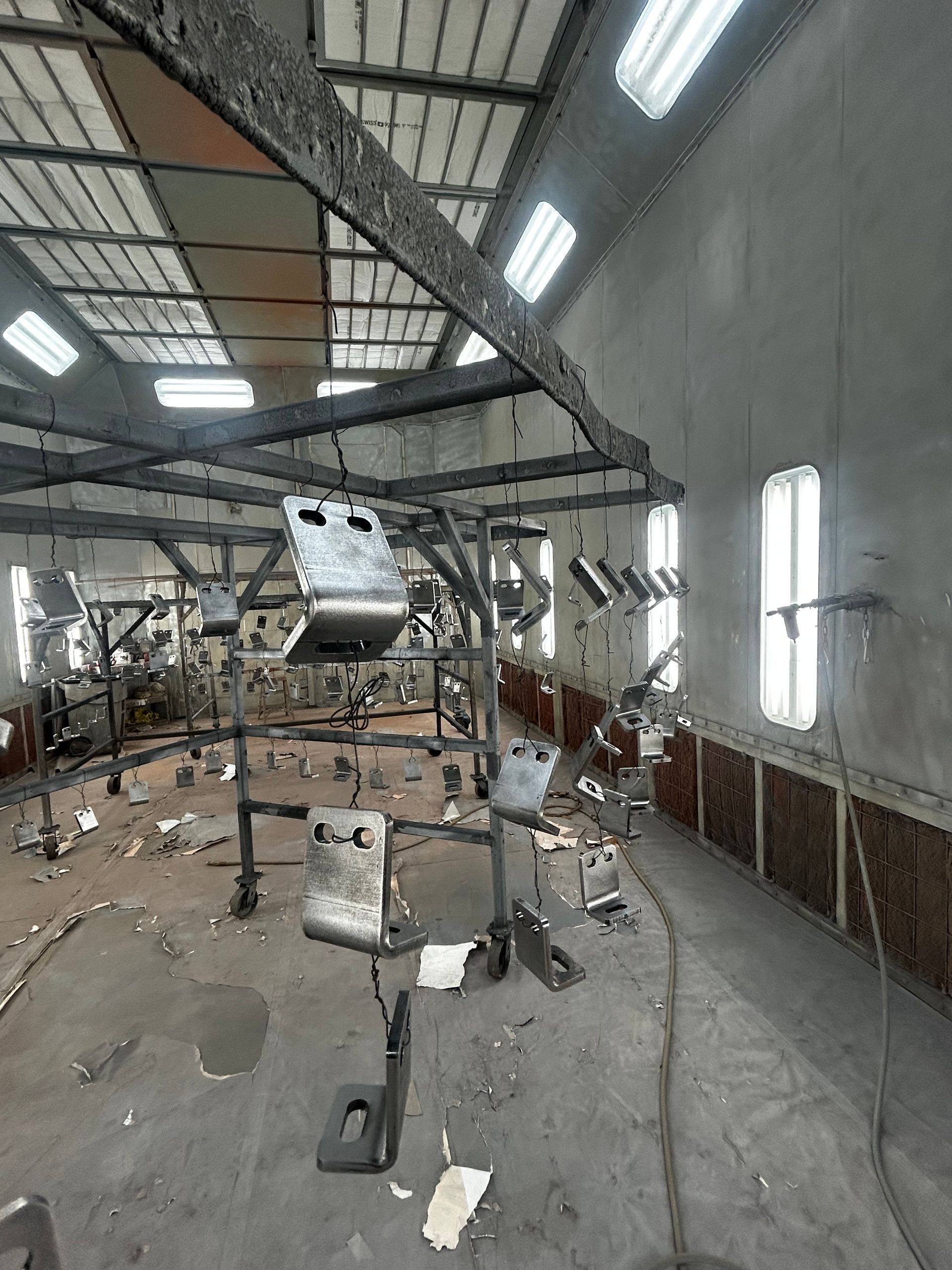 Damaged industrial warehouse with scattered debris, broken machinery, and a crumpled metal panel on the floor