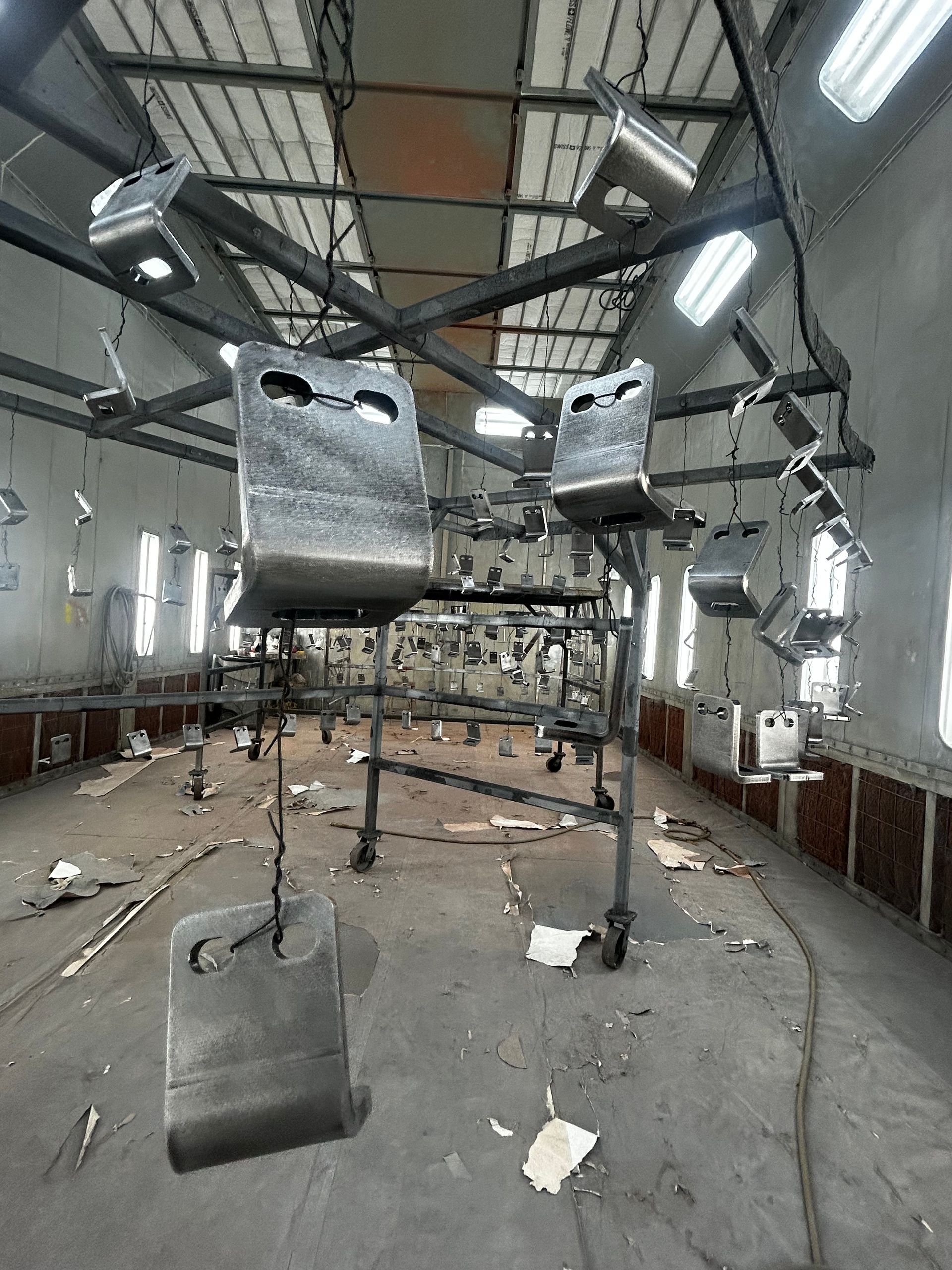 Damaged indoor room with shattered ceiling and debris, hanging metal objects, and broken windows