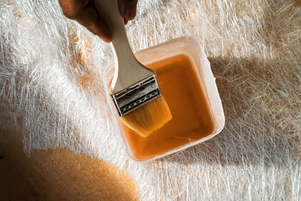 Paintbrush dipped in orange liquid beside a white fur-like surface