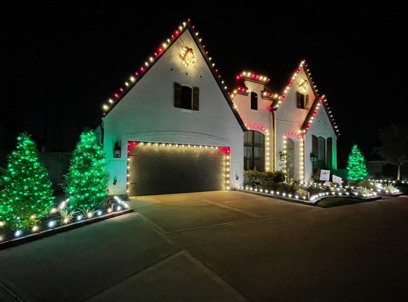 House decorated with red and white Christmas lights, a lit snowman, and cars parked in front.