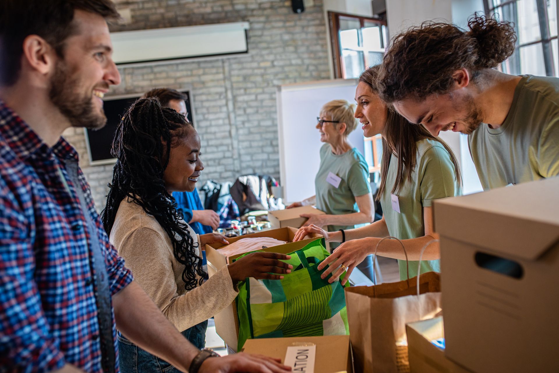 People sorting donations into cardboard boxes at a community drop-off table