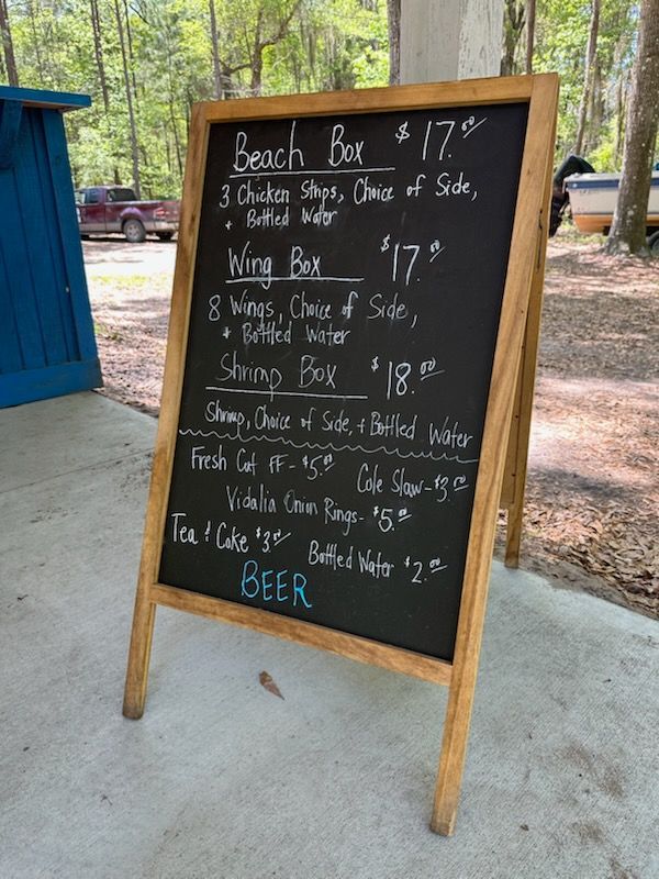 Menu board with food items for sale, like chicken strips and wings.