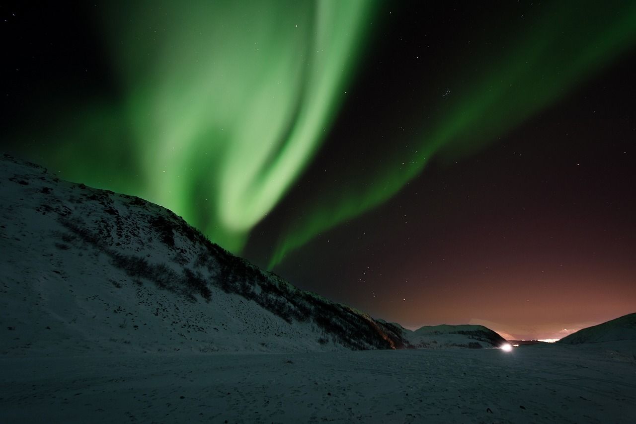 The aurora borealis is shining over a city at night.