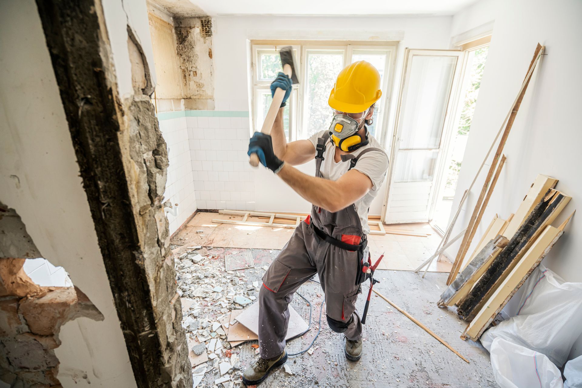 A construction worker is breaking a wall with a hammer.