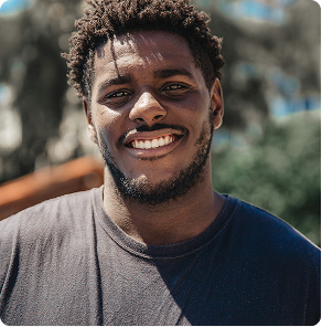Smiling man in a dark shirt outdoors in daylight