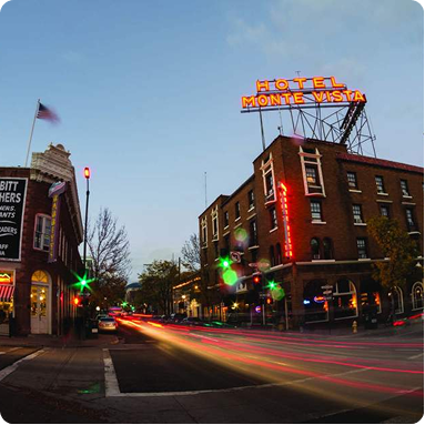 Nighttime street scene with Hotel Monte Vista neon sign and car light trails at an intersection