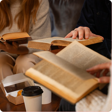People reading open books around a coffee cup in a cozy indoor setting