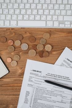 Wooden desk with scattered coins, paperwork, a pen, and a white keyboard at the top.