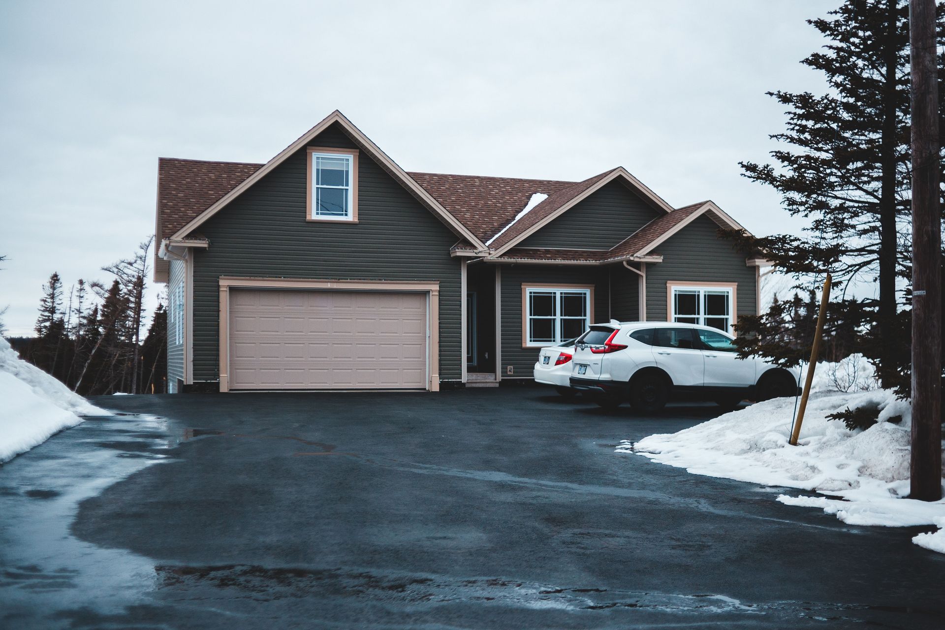 Snowy suburban house with a white SUV parked in the driveway