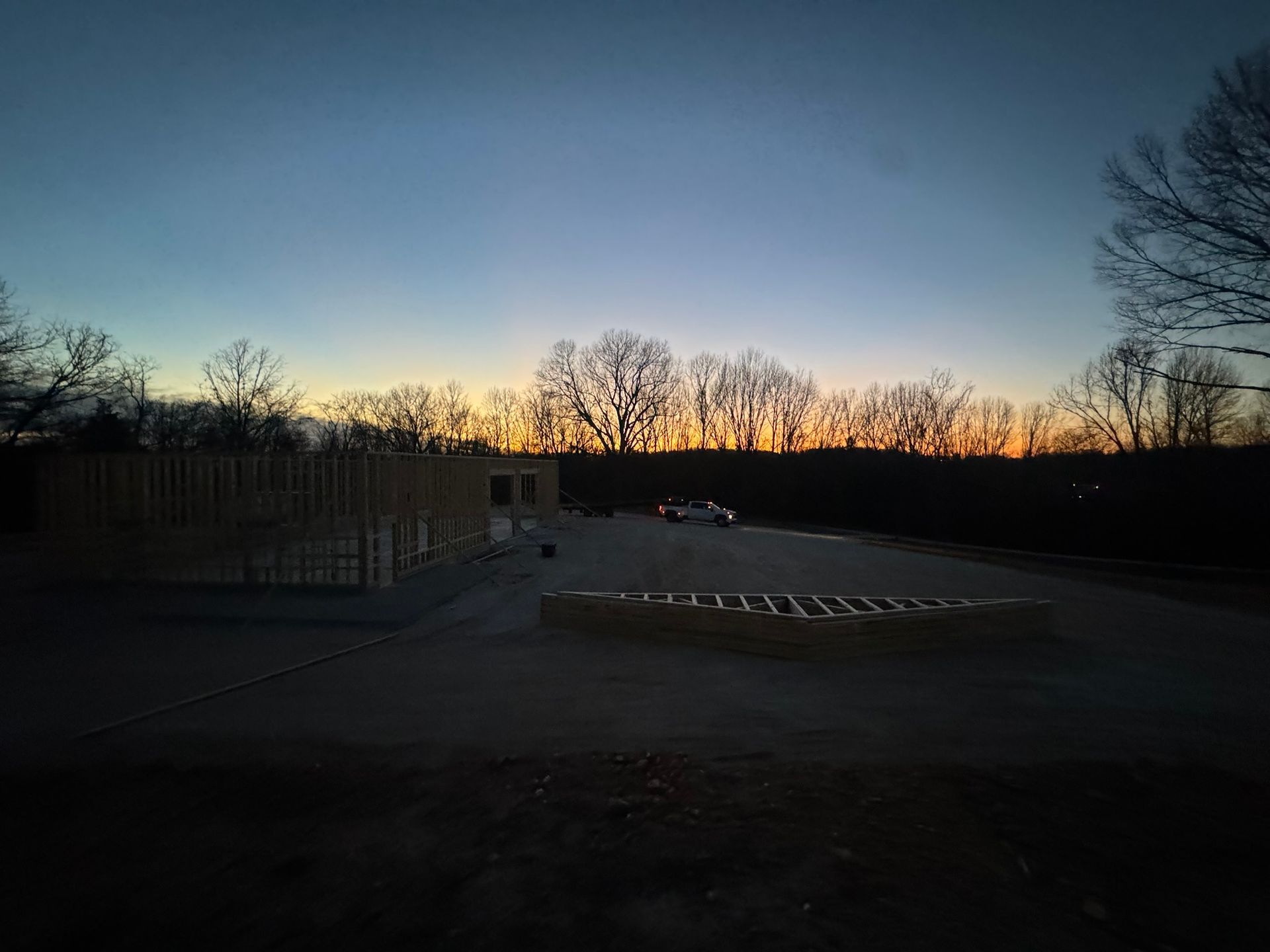 Dusk over an empty parking lot with bare trees silhouetted against a blue-orange sky.