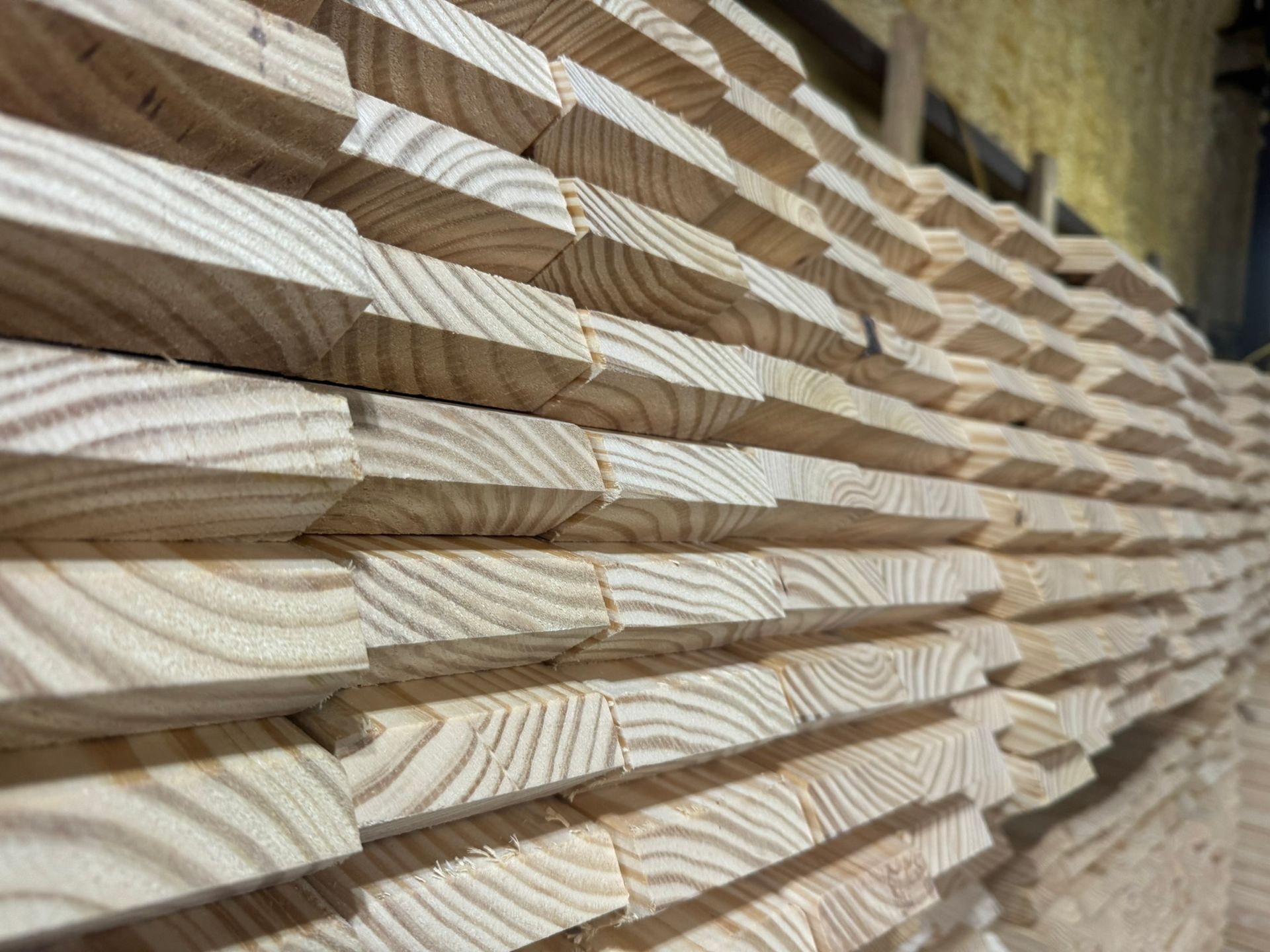 Stacked light wood boards with angled cut ends in a lumberyard