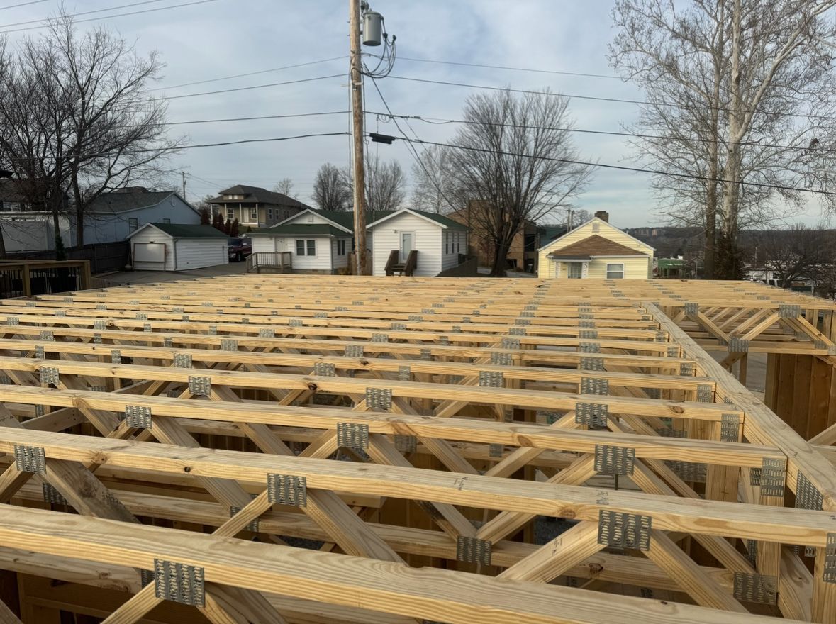 Wooden roof trusses under construction on a house foundation in a residential neighborhood