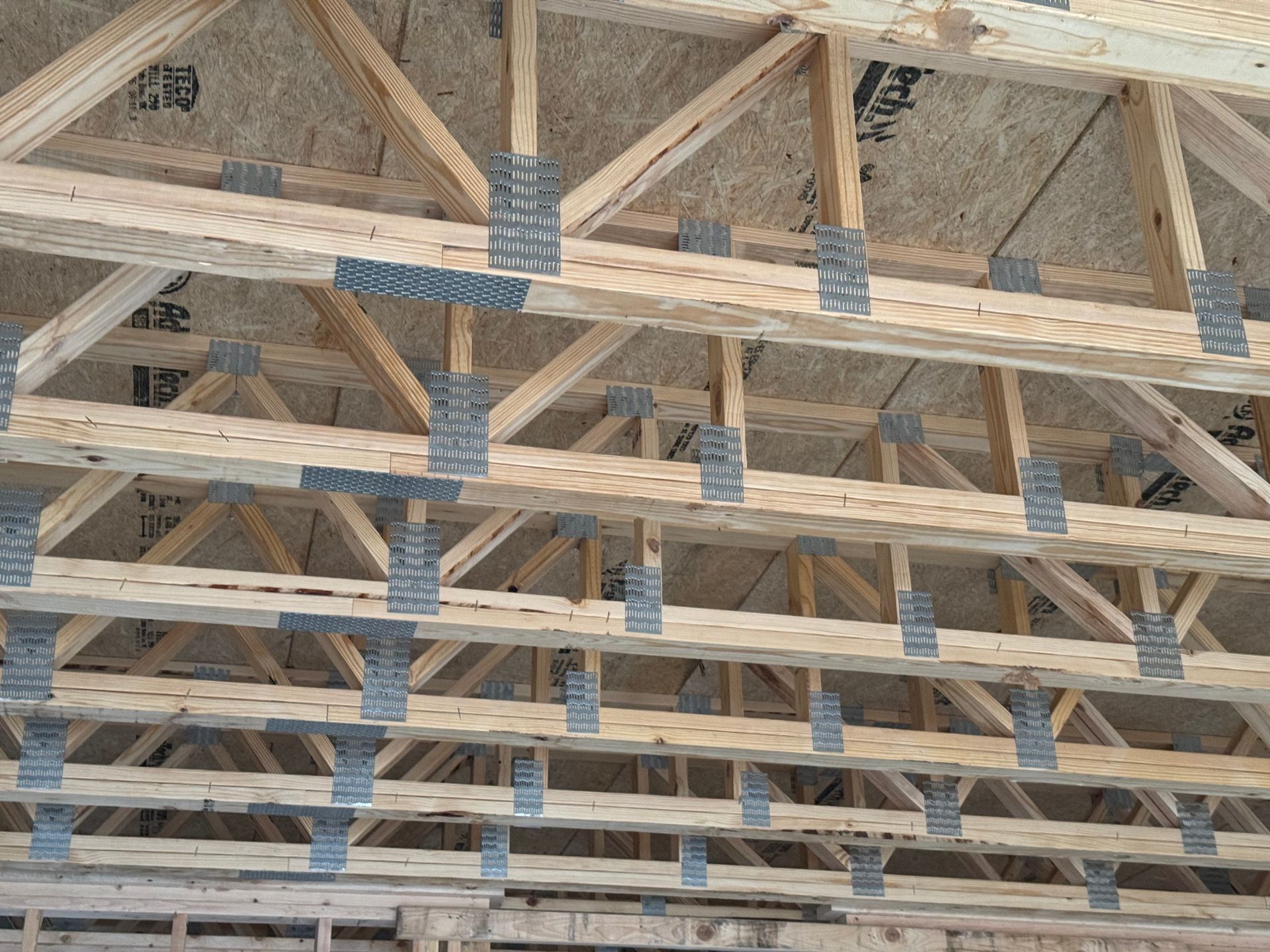 Wooden roof trusses with blue metal connectors in a construction frame