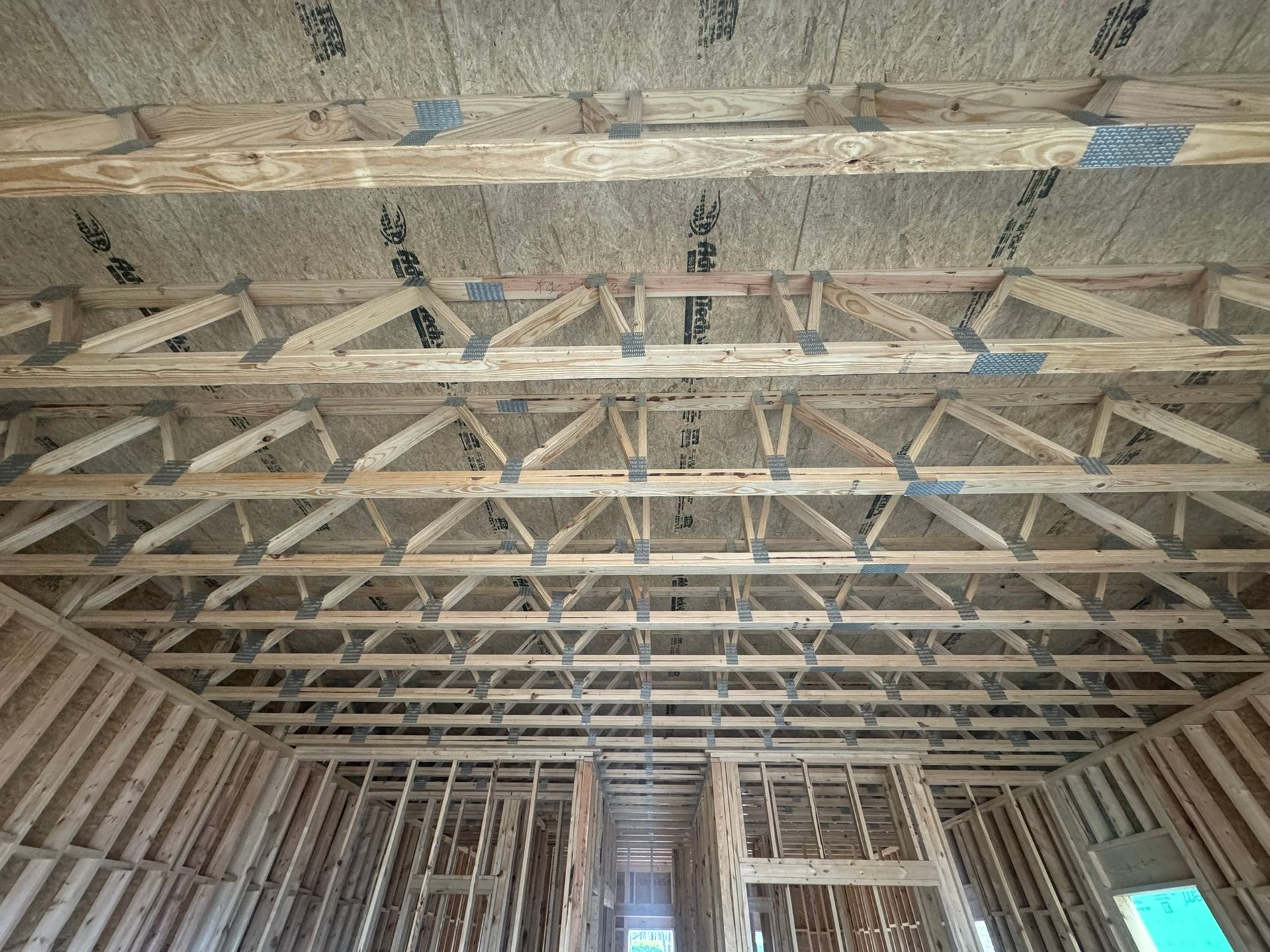 Interior of a house under construction with exposed wooden roof trusses and insulation