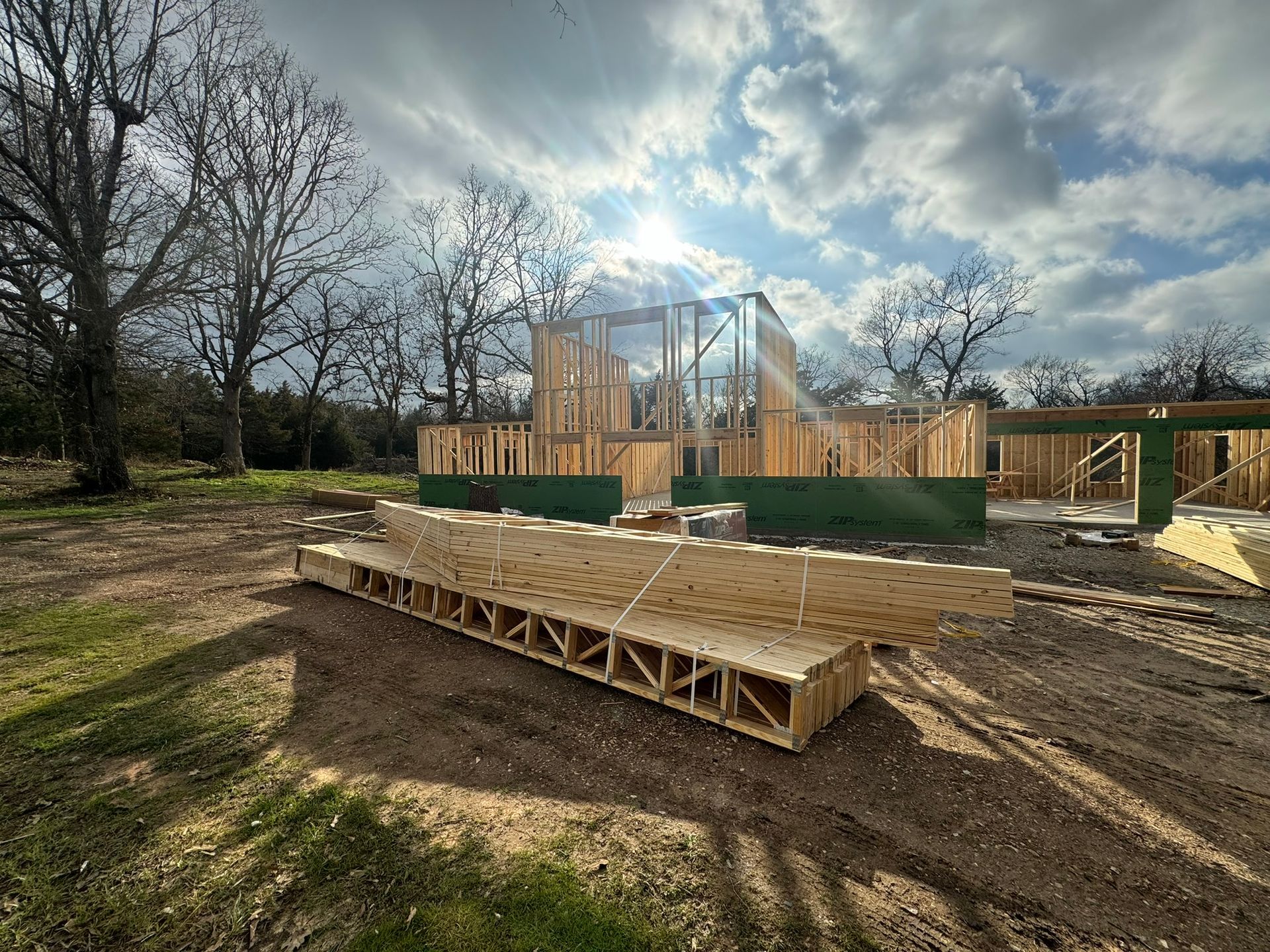House foundation under construction with wooden framing, green barriers, and a cloudy sky