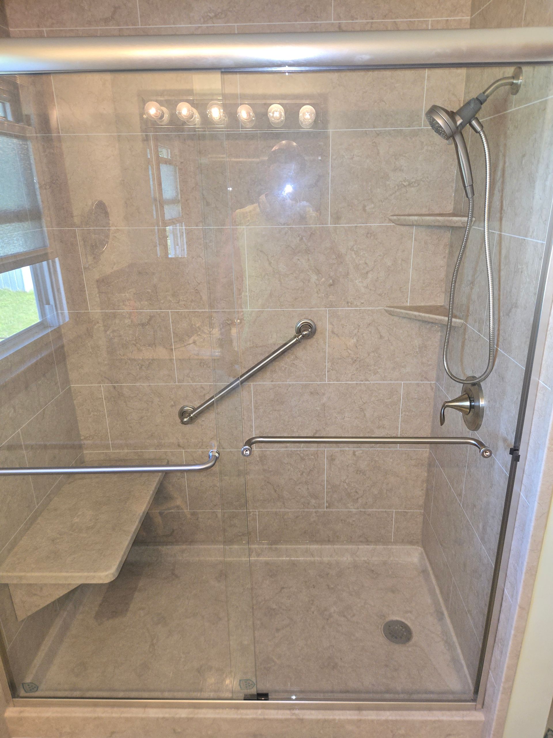 White accessible shower stall with grab bar and chrome fixtures.