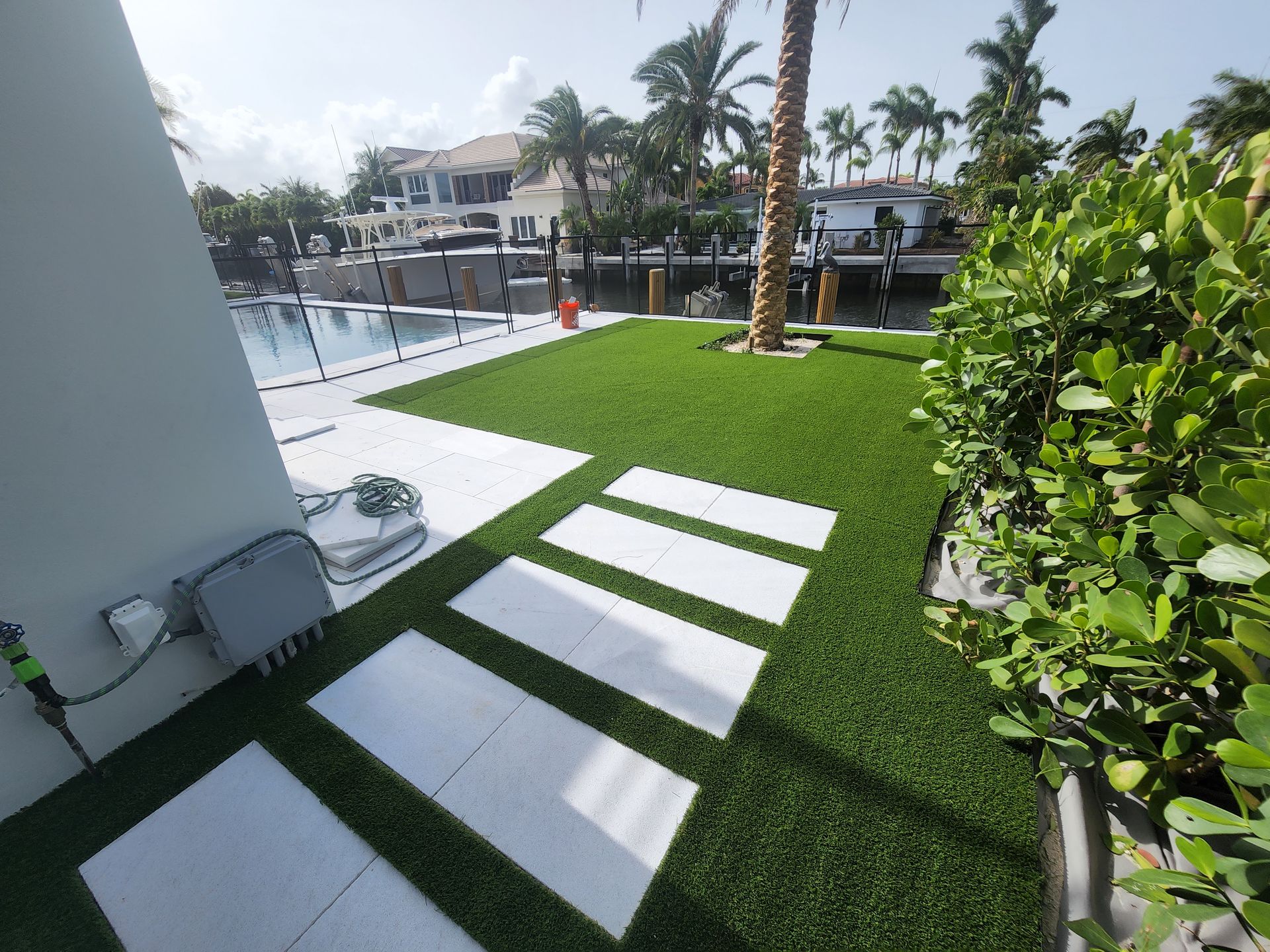 A lawn with white tiles and a palm tree in the background