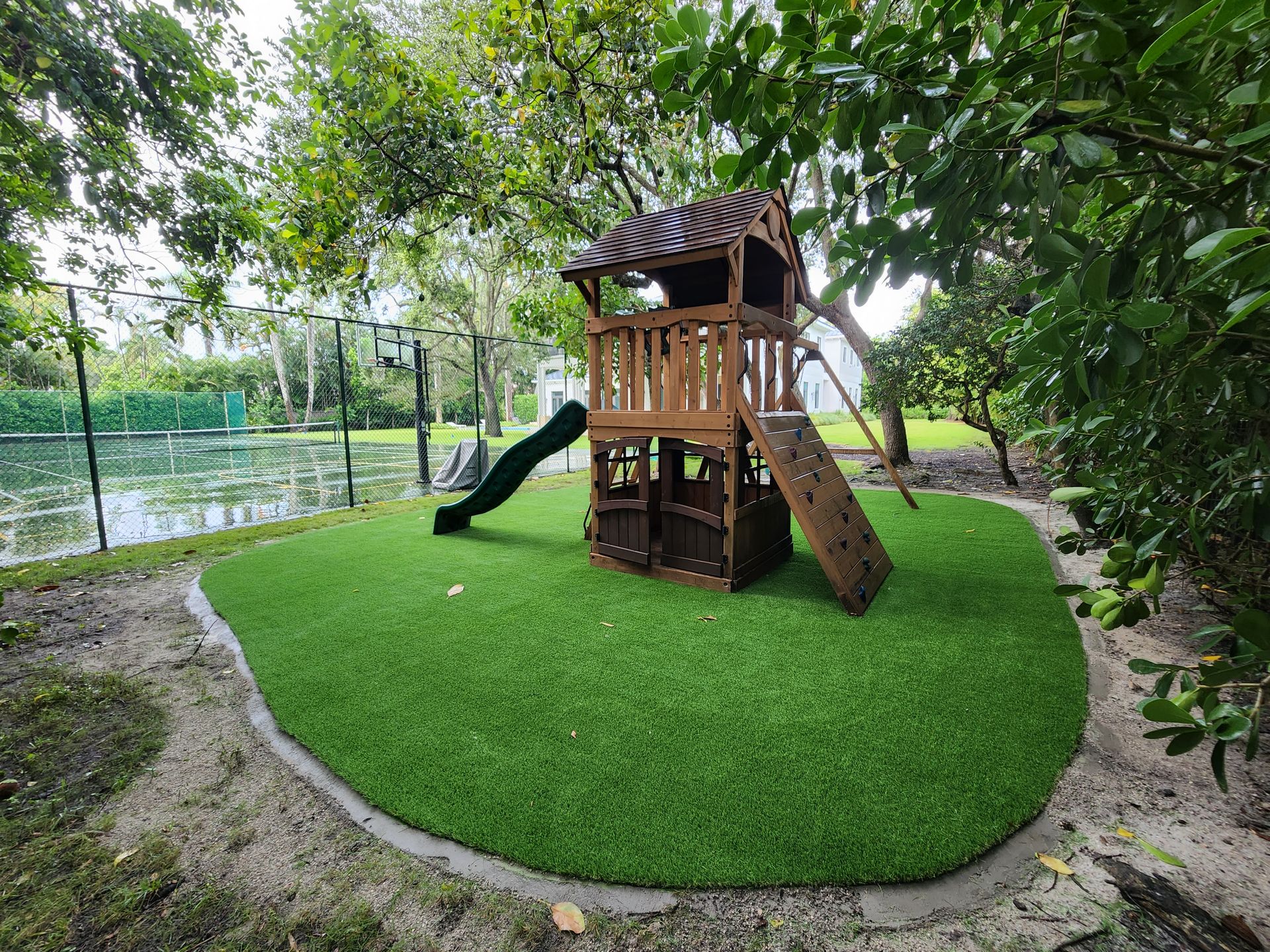 A wooden playground with a slide and climbing wall in a park.