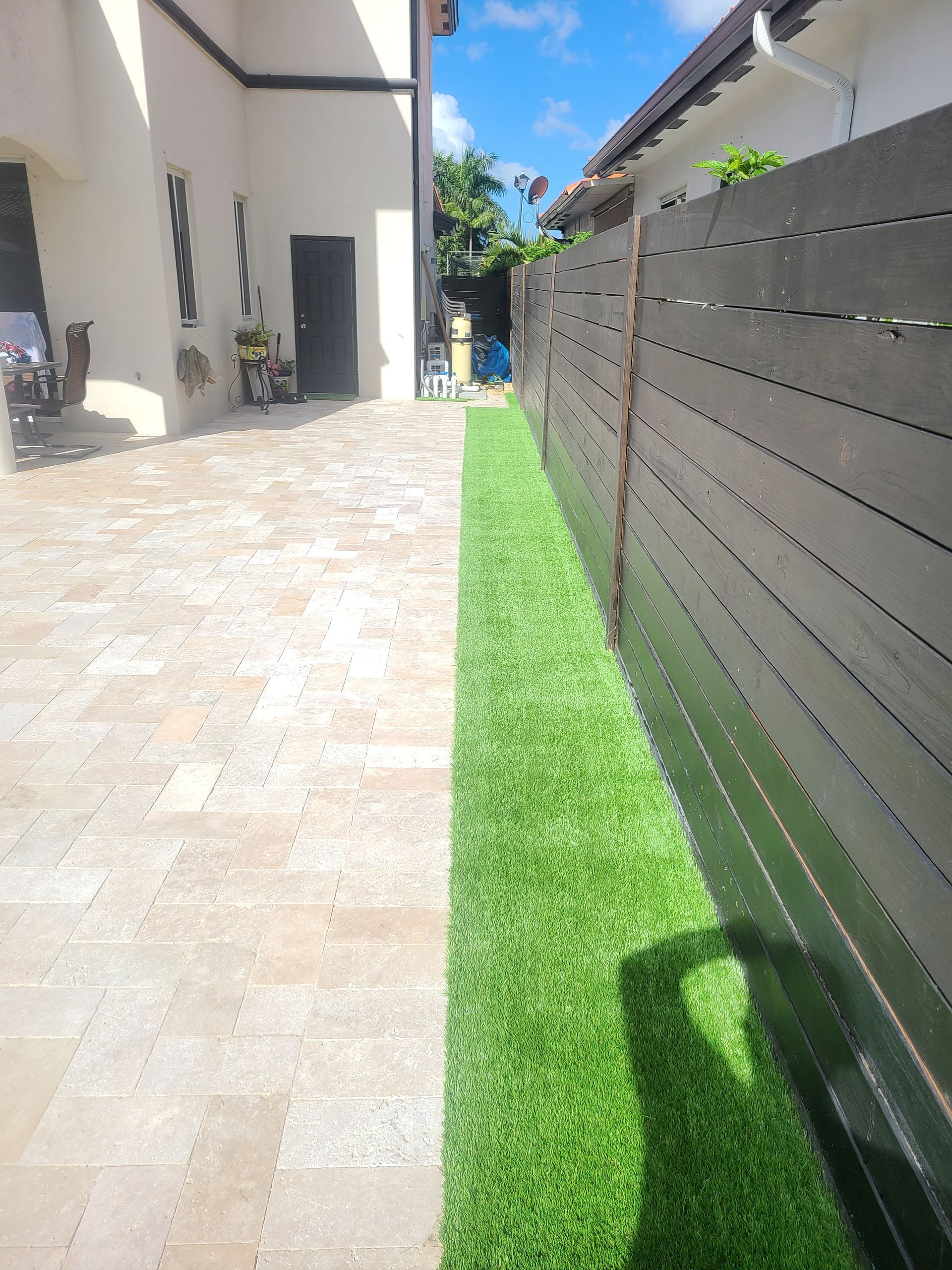 A wooden fence surrounds a lush green lawn in front of a house.