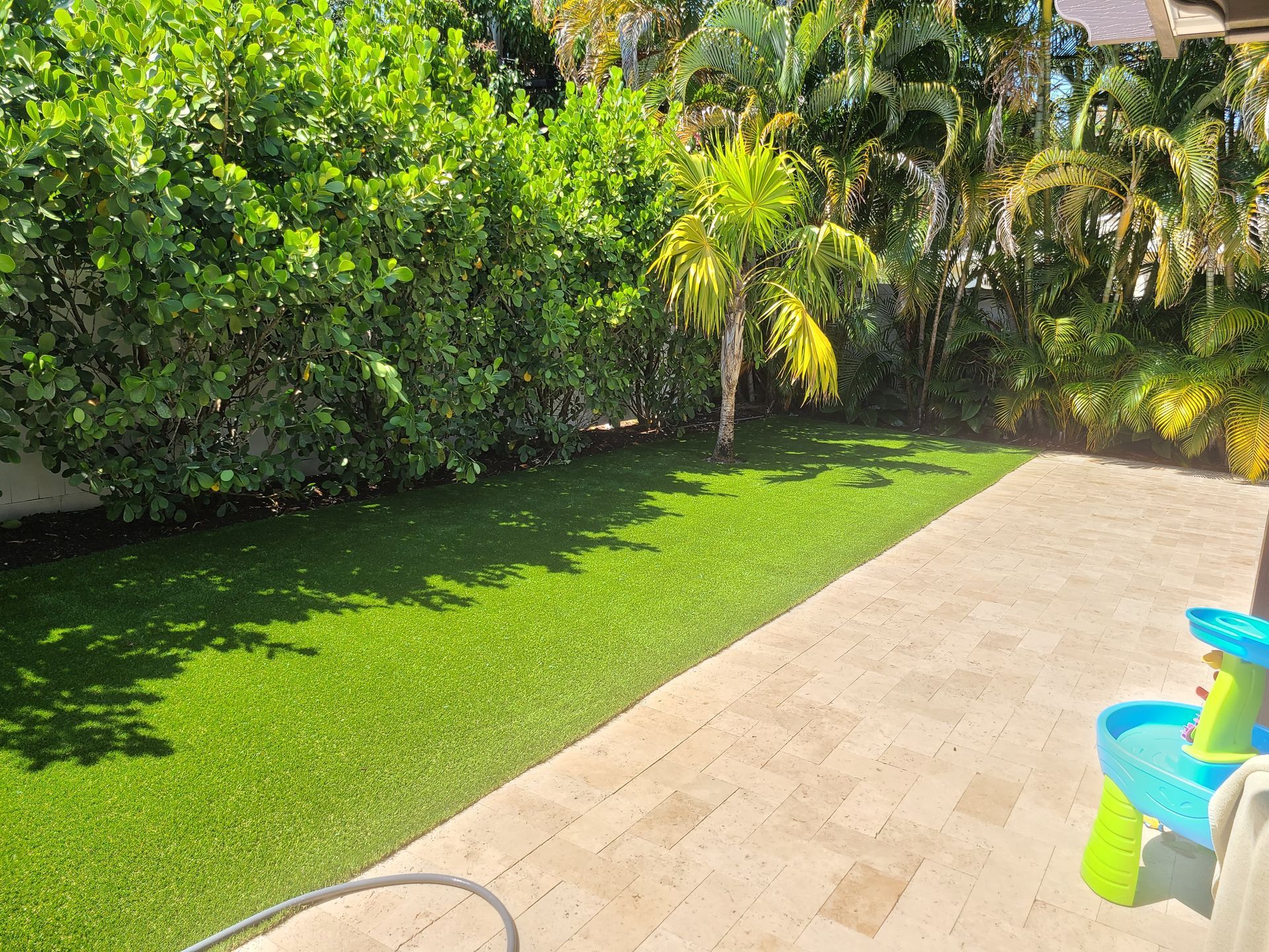A backyard with a lush green lawn and a patio.