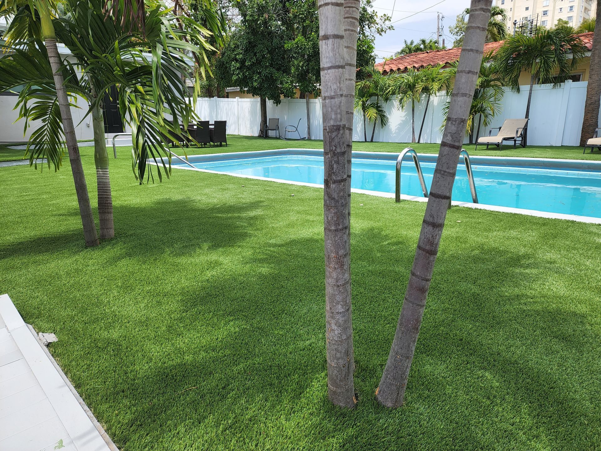 A large swimming pool surrounded by palm trees and lush green grass.