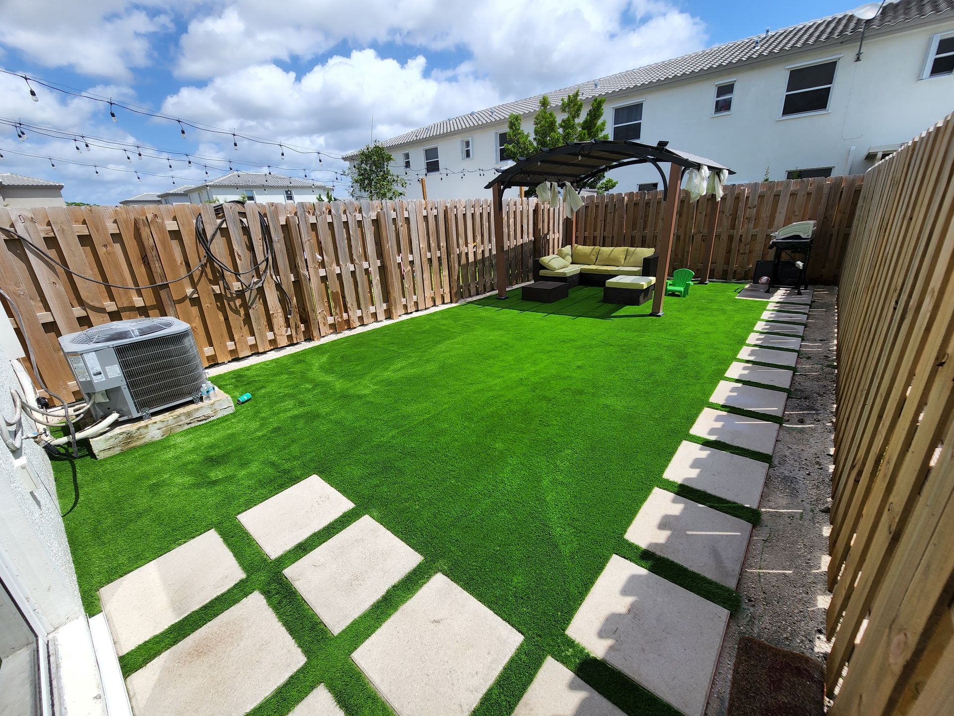 A backyard with a wooden fence and a lush green lawn.
