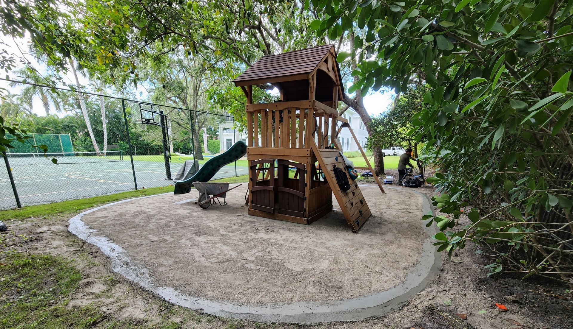 A wooden playground with a slide and swings in a park.