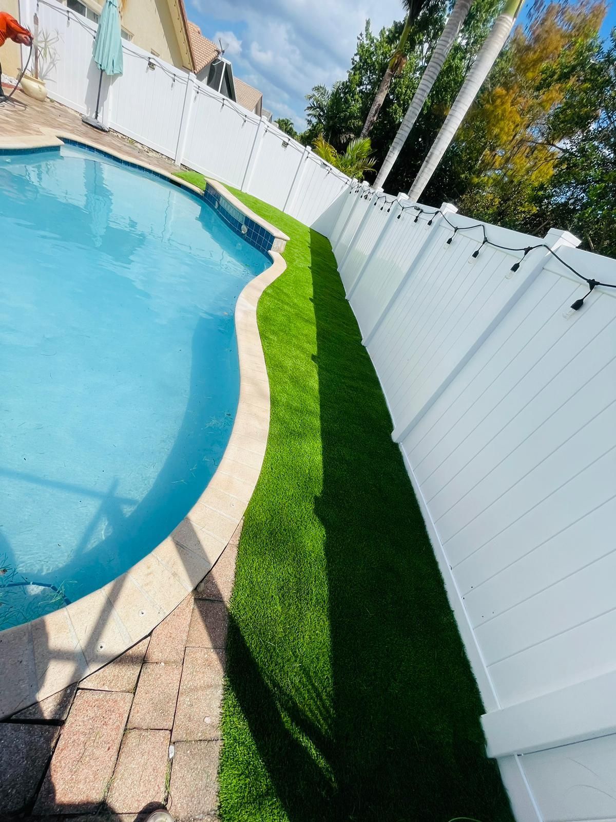 A swimming pool surrounded by a white fence and grass.