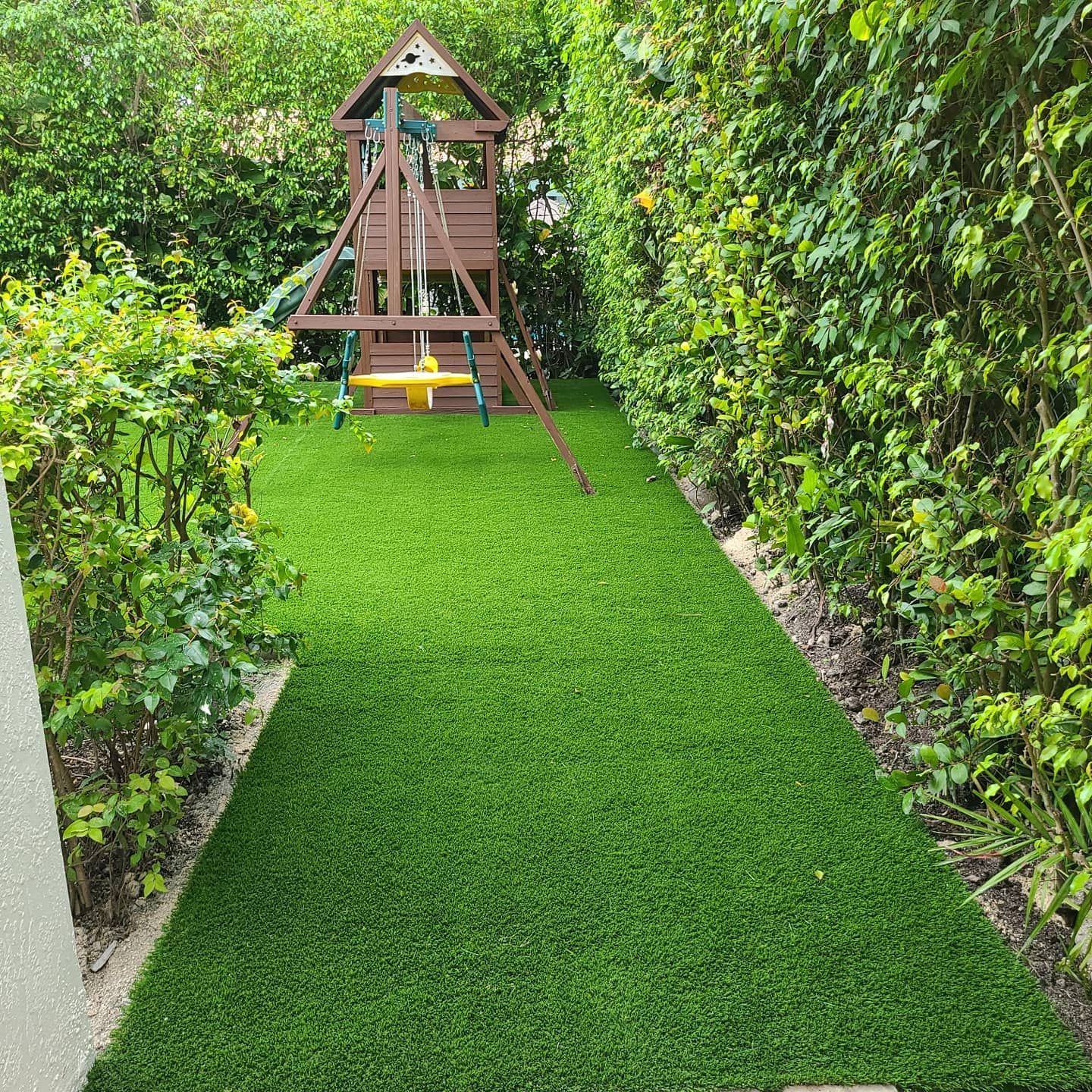 A backyard with a playground and a lush green lawn.
