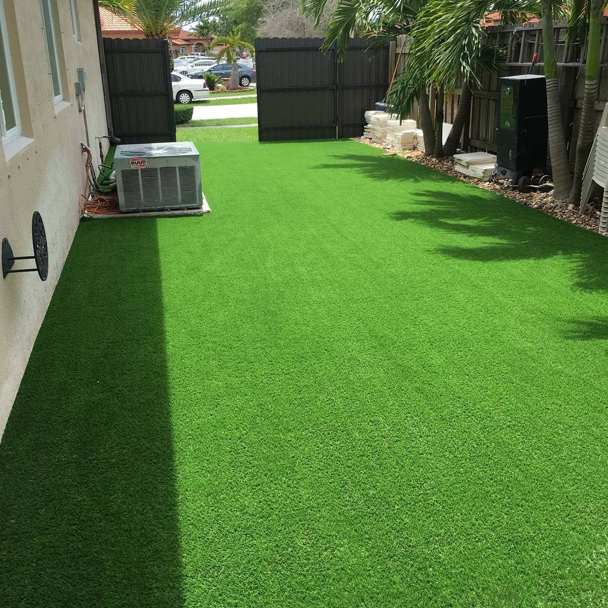 A backyard with a lot of green grass and a fence.