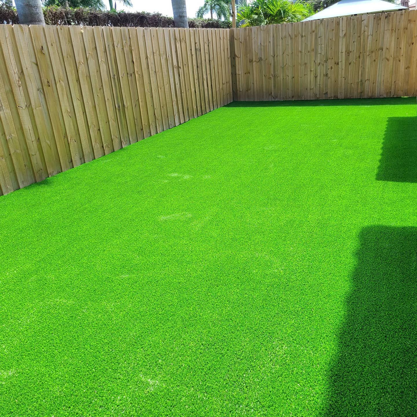 A backyard with a wooden fence and a lot of green grass.