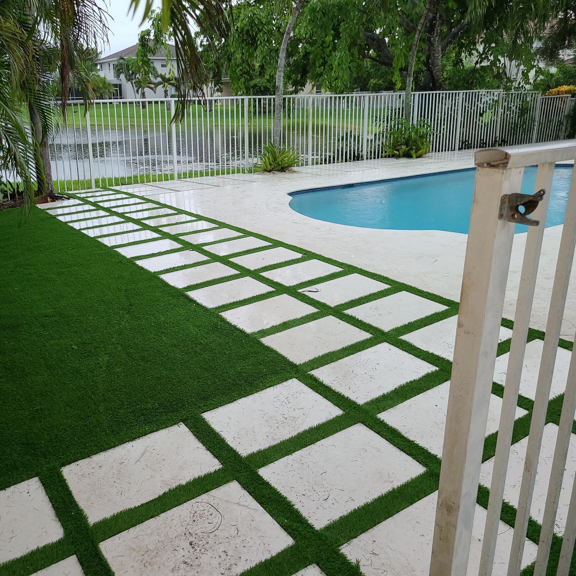 A fence surrounds a swimming pool with a walkway leading to it
