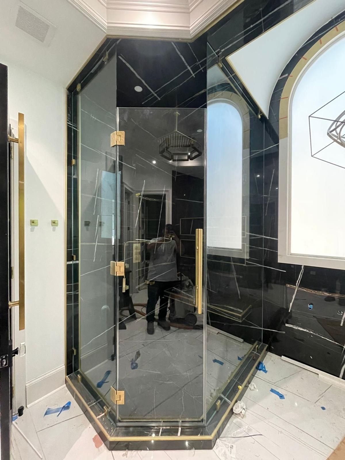 Glass shower enclosure with black marble walls in a tiled bathroom under construction