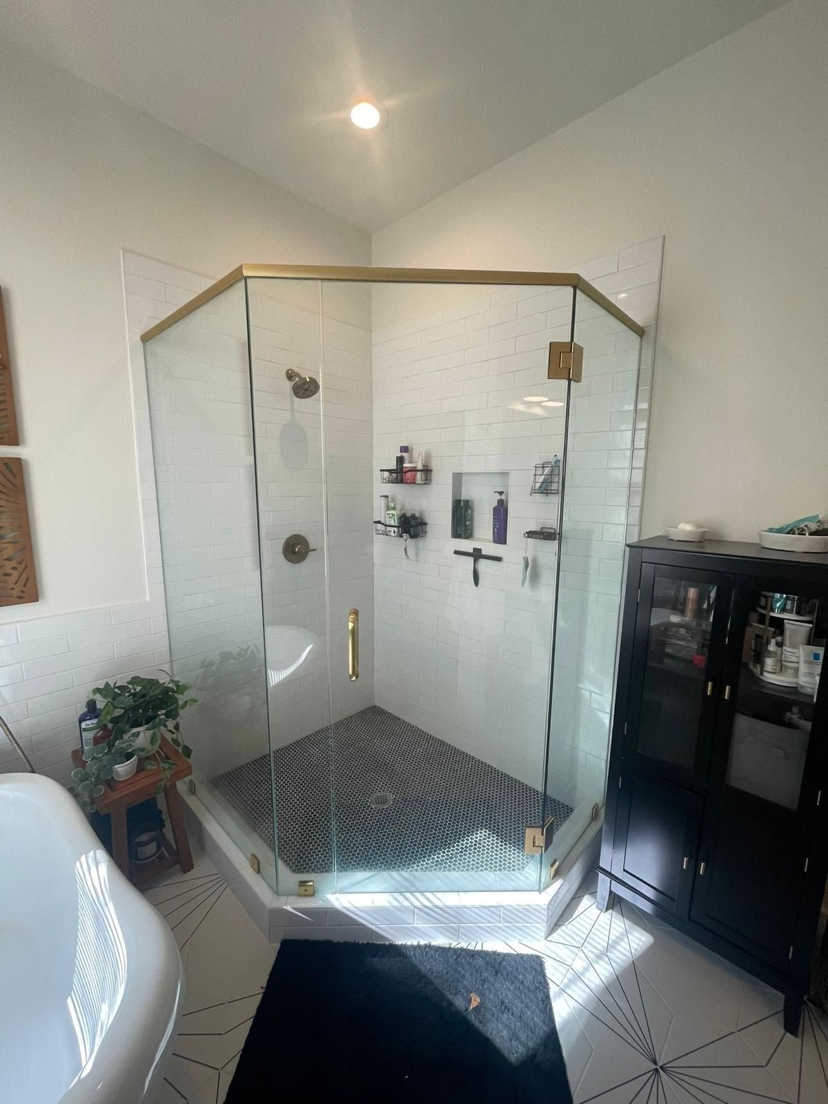 Corner shower enclosure with clear glass doors and tiled floor in a bright bathroom