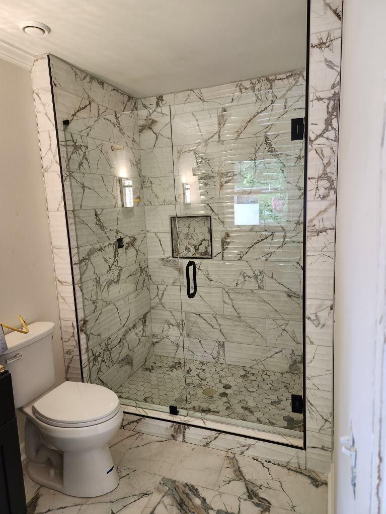 Bathroom with marble-look walk-in shower, glass door, and toilet on the left.