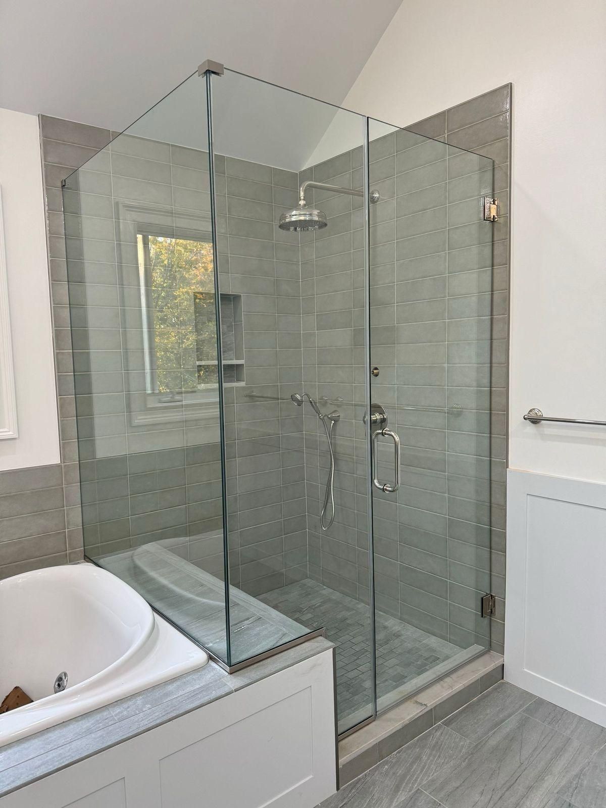 Glass shower enclosure next to a white bathtub in a modern bathroom