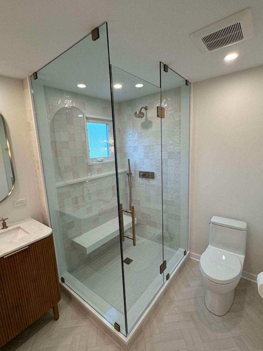 Modern bathroom with glass shower enclosure, white toilet, and wood vanity