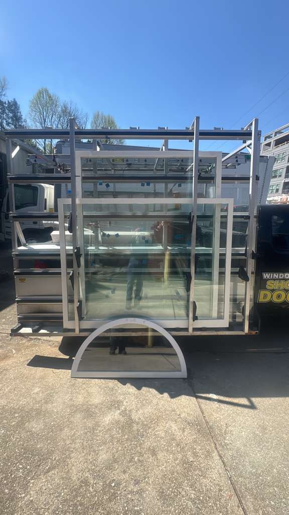 Glass storefront panels stacked on a trailer outdoors under a clear blue sky