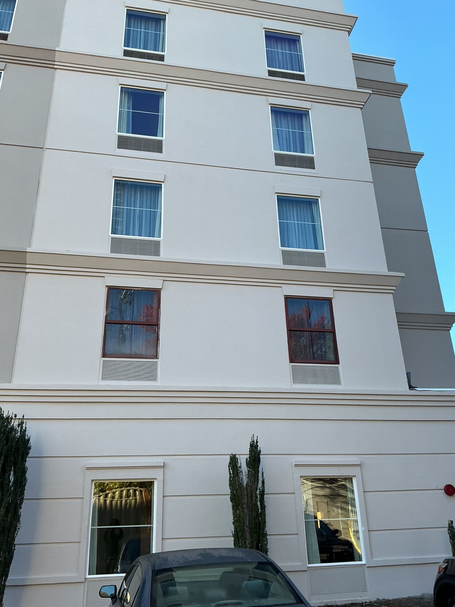 White multi-story apartment building with balconies and parked cars in front