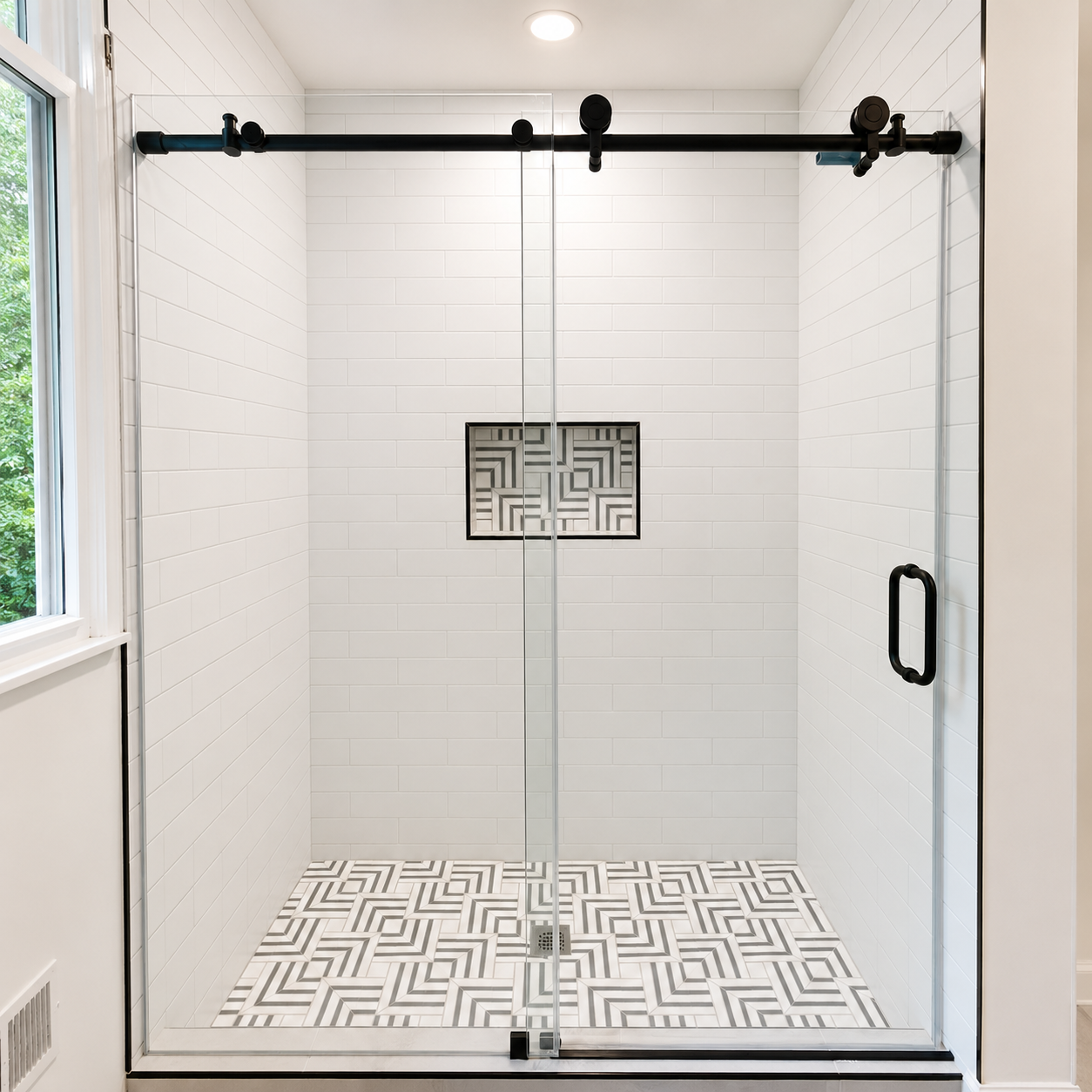 Modern glass shower with white tiled walls and geometric floor and accent tile.