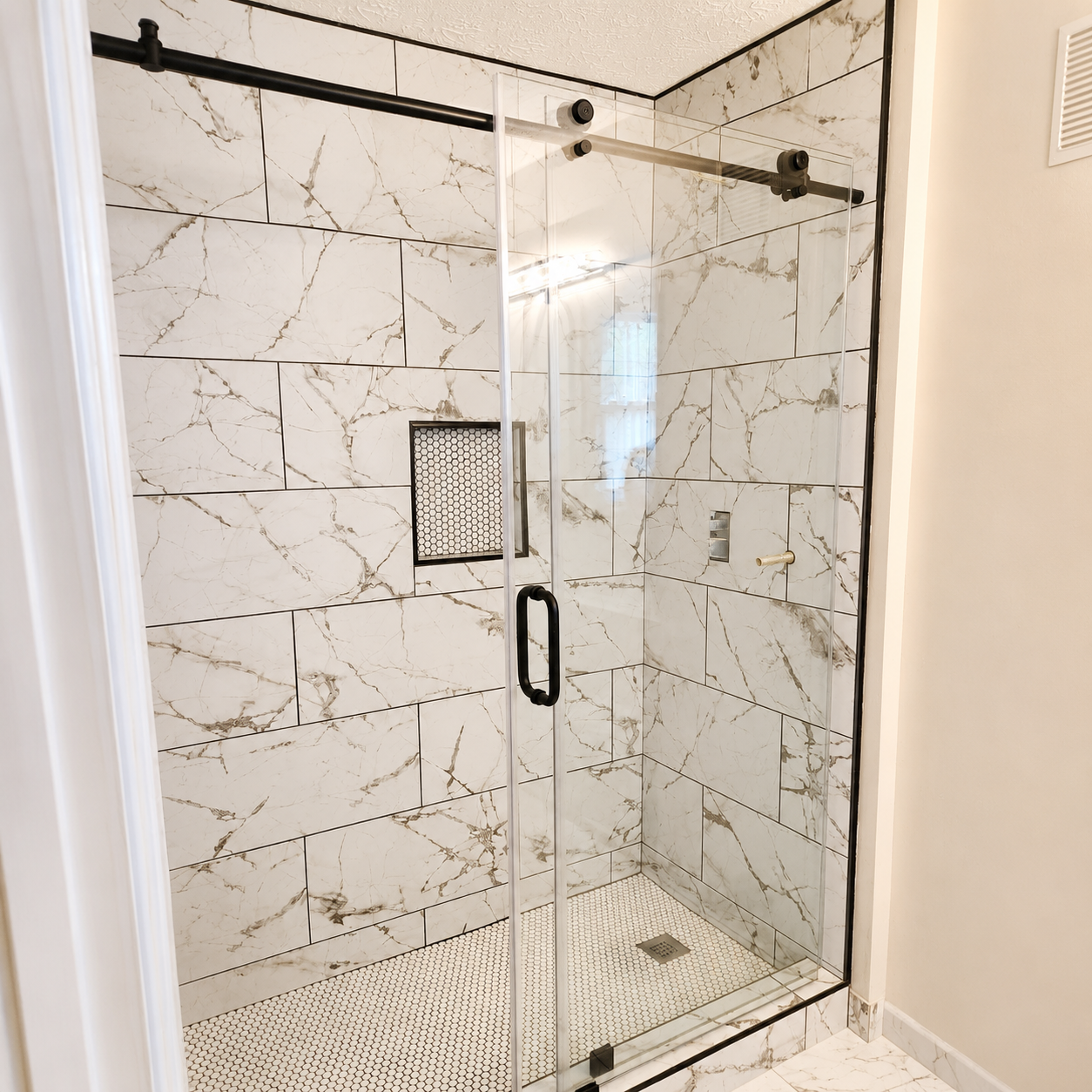 Glass shower enclosure with white tiled walls and a built-in shelf in a bathroom
