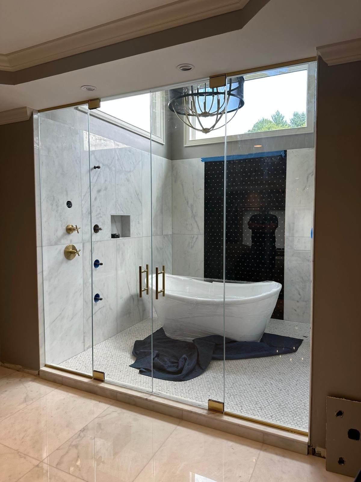 Modern glass-enclosed shower with a freestanding white tub in a marble bathroom