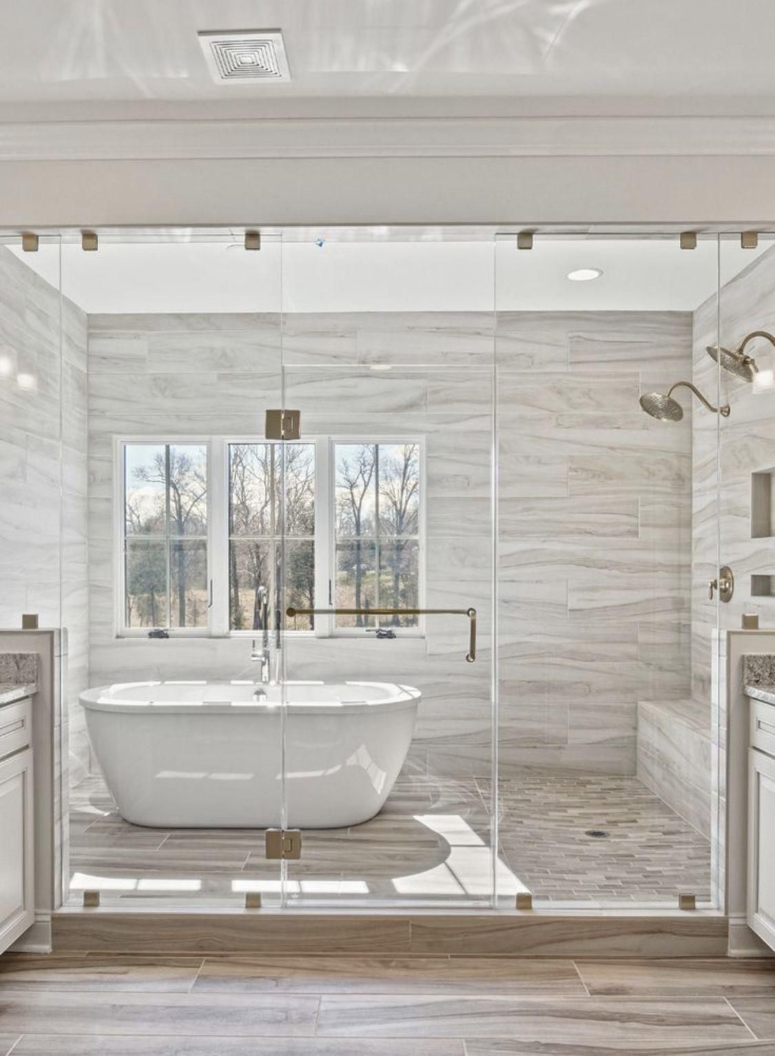 Bright modern bathroom with freestanding tub behind a glass shower enclosure and wood-look flooring.