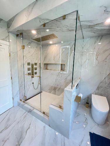 Modern marble bathroom with glass-enclosed shower and white toilet