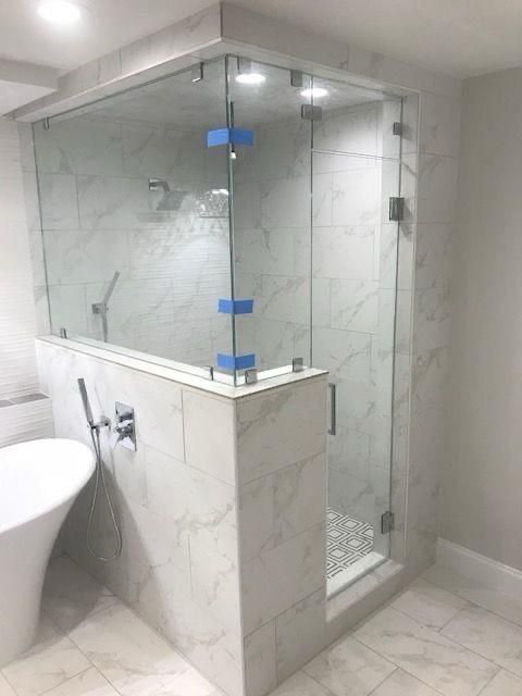 Modern white marble bathroom shower with glass enclosure and partial view of a toilet