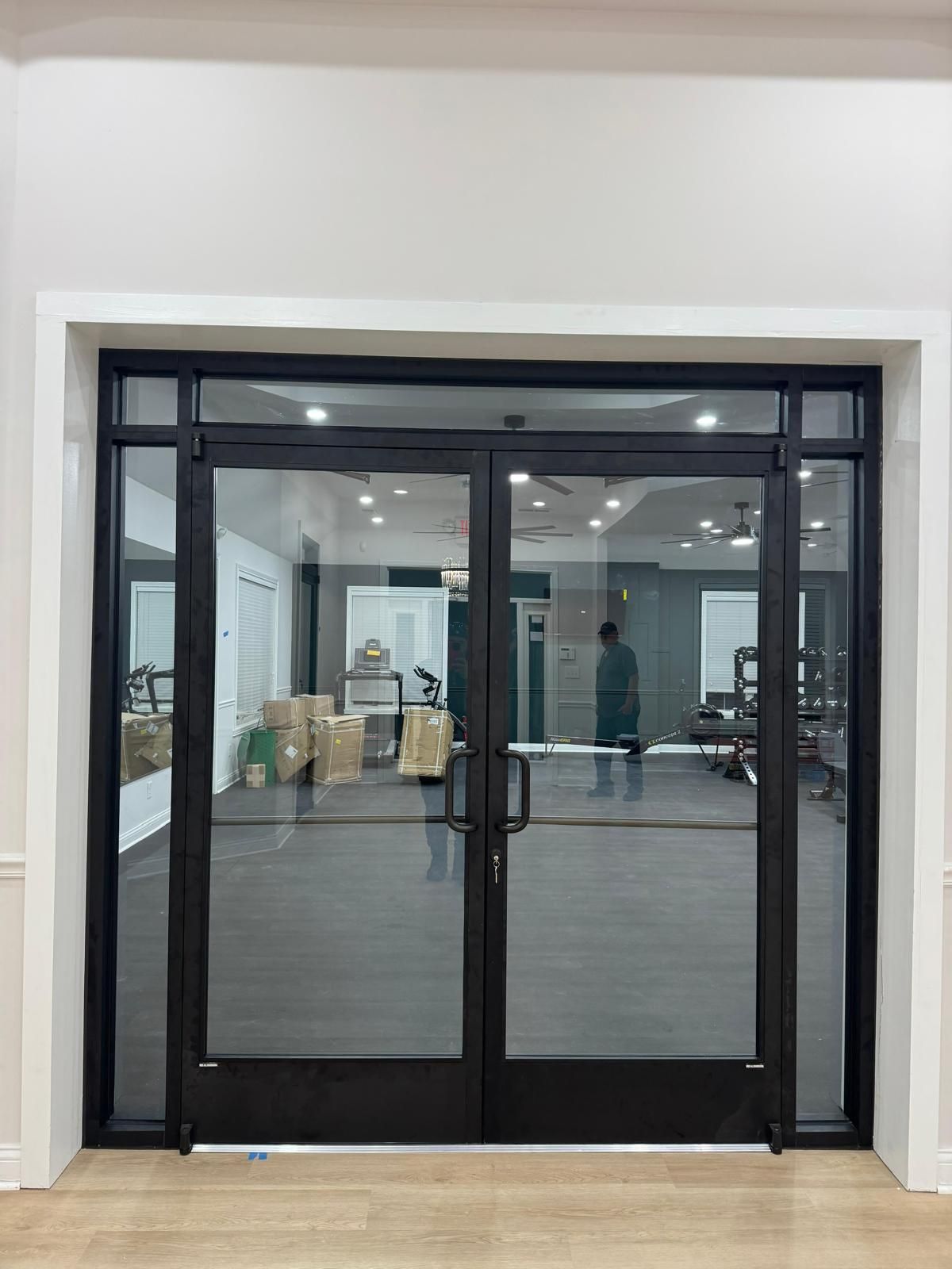 Black-framed glass double doors opening into a bright interior space